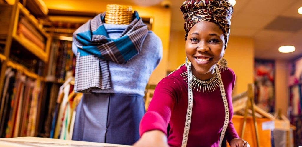 tanzanian woman with snake print turban over hear working in fabrics shop.